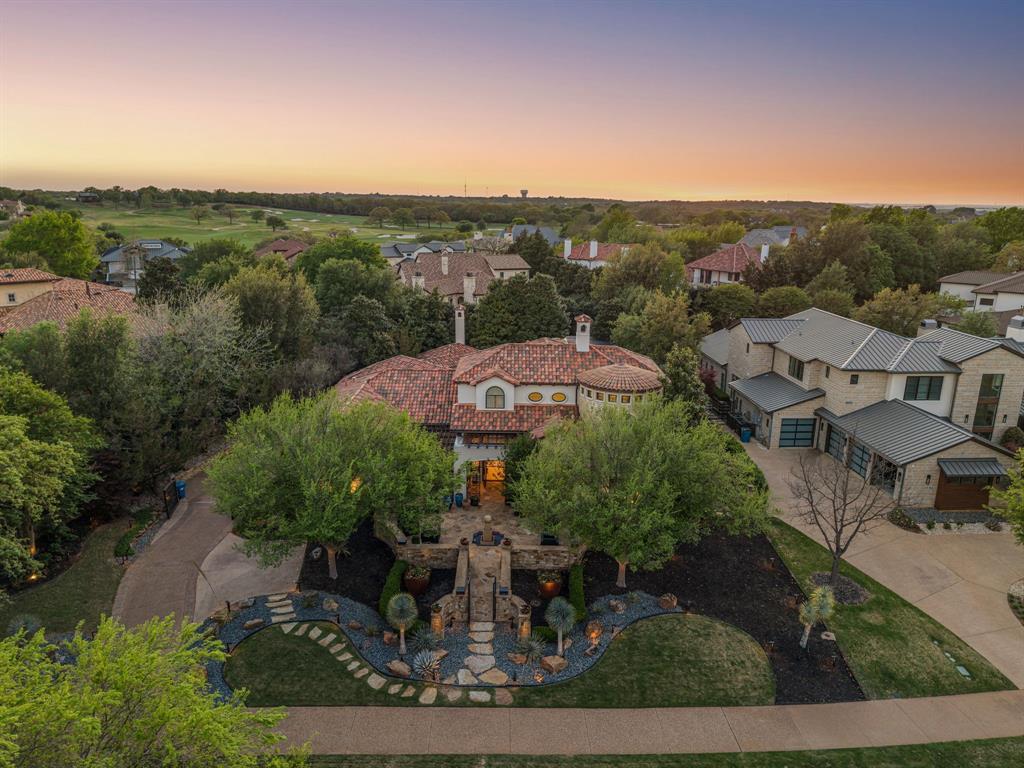 Aerial view of the full estate at dusk, tile roof and circular turret wing, motor court and stone entry path, with the golf-course fairway beyond.