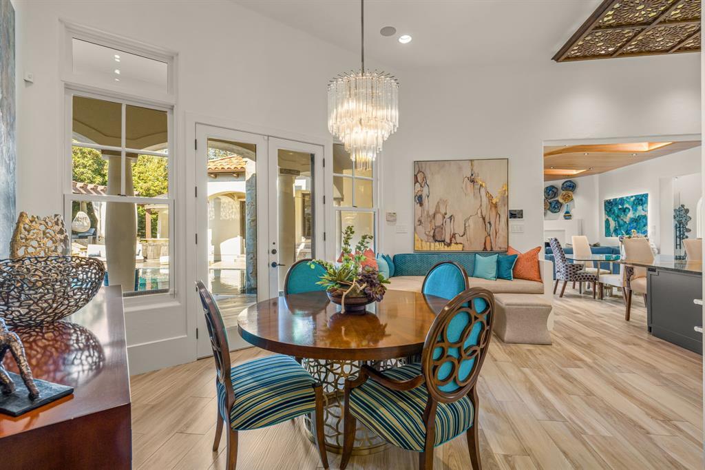 The dining looking back toward the courtyard doors: the crystal chandelier and round table, glass doors framing the pool loggia, and a sightline down the length of the house.